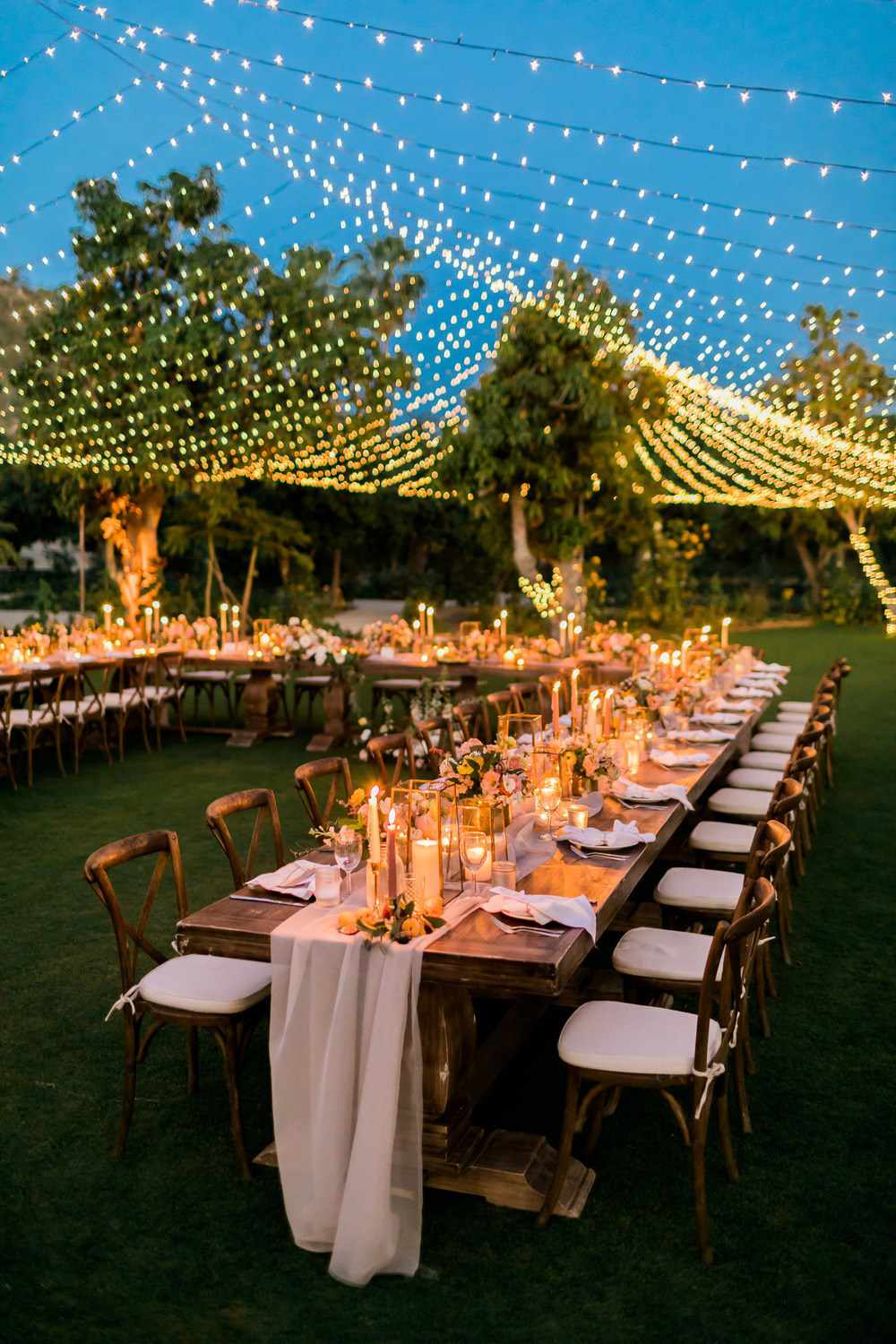 Monox outdoor event setup — long banquet table under fairy lights at dusk